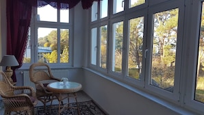 A room with a large window, wicker chairs, a small table, and a lamp. - Apartment "Villa Adler - Seeblick" with Lake View (Seebad Ahlbeck)