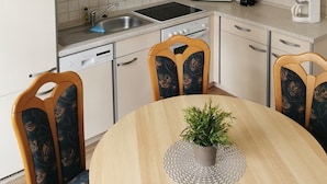 A kitchen with white cabinets, a microwave, a coffee maker, and a chandelier. - Apartment "Villa Adler - Seeblick" with Lake View (Seebad Ahlbeck)
