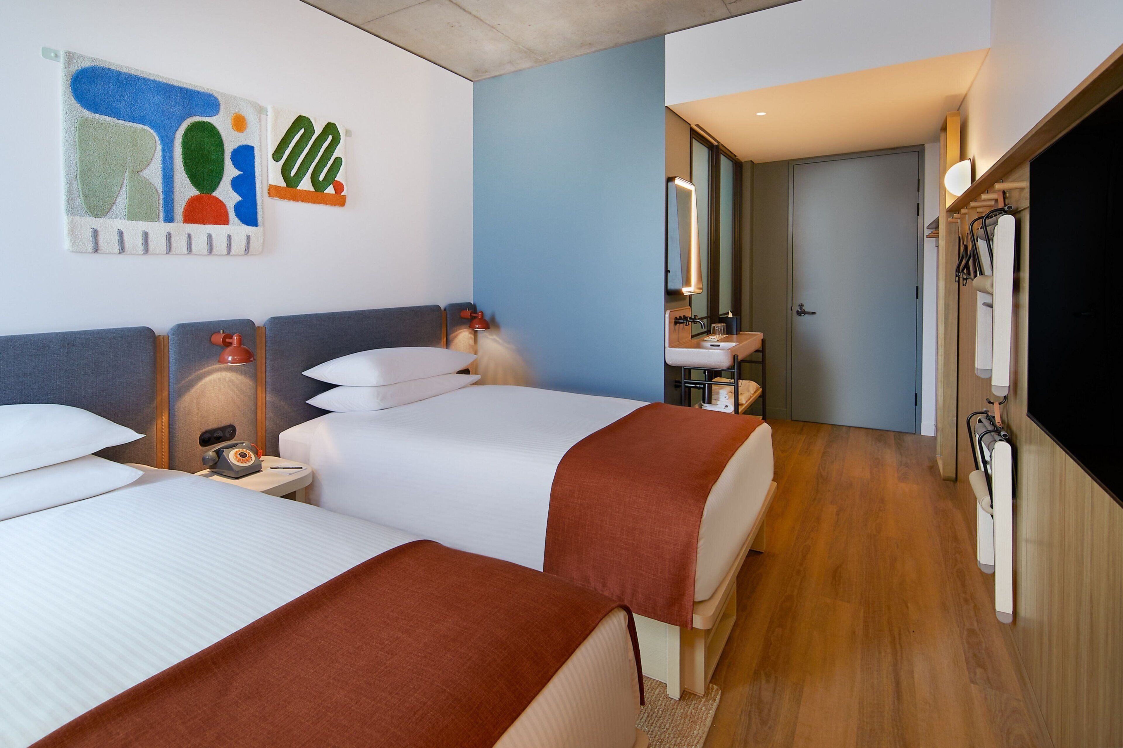 Habitación de hotel con dos camas, baño y televisor.