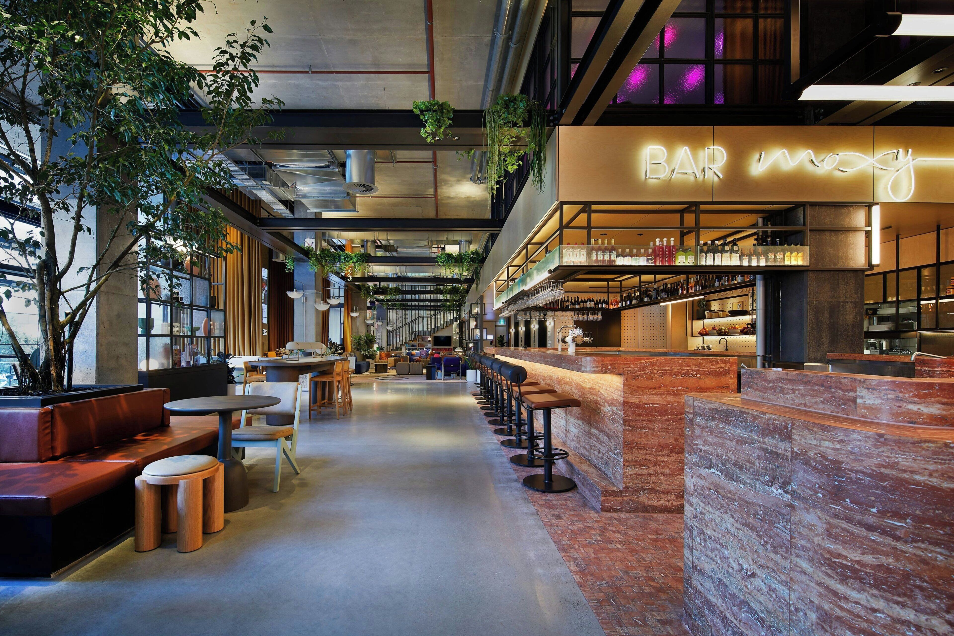 A modern bar area with seating and a neon sign.