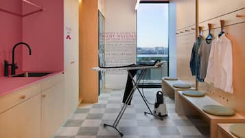 A modern, well-lit room with a checkered floor, a sink, a drying rack, and a wall-mounted clothing rack.