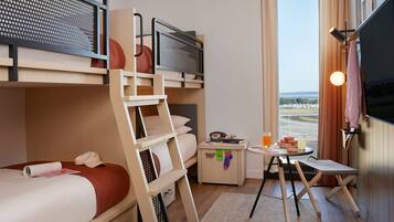 Una habitación de hotel con literas, una mesita con una bebida y un televisor.