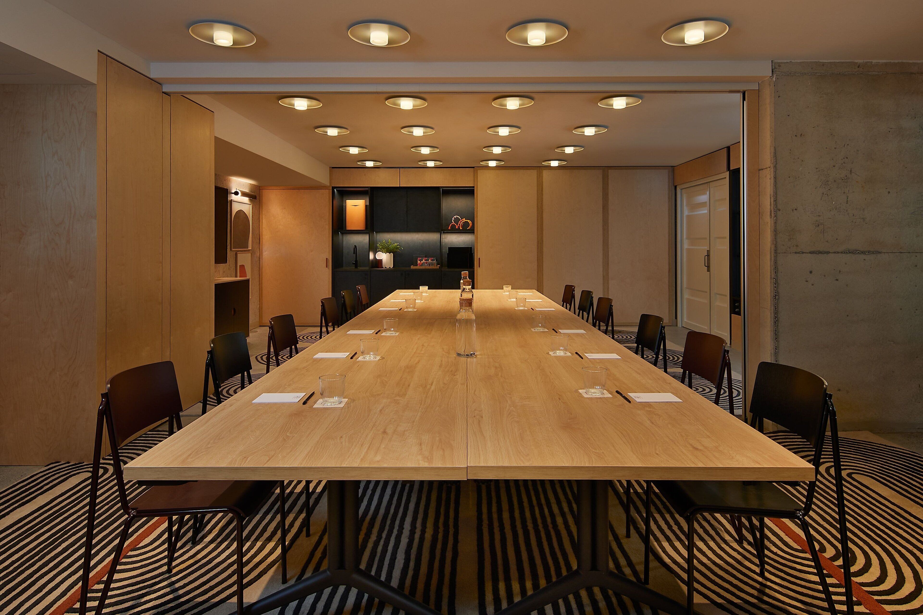 A conference room with a long table, chairs, and a patterned carpet.