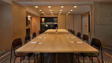 A conference room with a long table, chairs, and a patterned carpet.