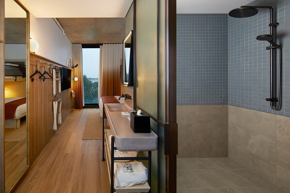 Un baño moderno con ducha, tocador con espejo y banca con toallas.