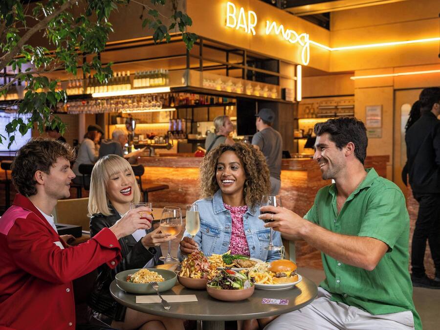A group of people dining at a restaurant with a bar in the background.