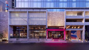 A modern building with a glass facade, a brick section, and a neon sign. - Moxy Sydney Airport (Mascot)