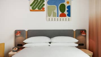 Una cama bien hecha con sábanas blancas, un cabecero gris y dos lámparas de noche.