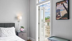 Ein Schlafzimmer mit einem Bett, einem Nachttisch, einem Tisch und Blick ins Freie.