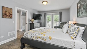 Une chambre à coucher avec un lit, une télévision, une armoire et une fenêtre avec des rideaux.