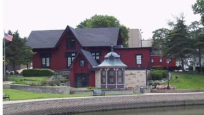 Un bâtiment rouge avec un socle en pierre, un petit jardin et un étang.