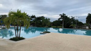 A swimming pool with palm trees and a cloudy sky.