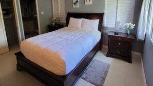 A bedroom with a bed, a nightstand, a dresser, a ceiling fan, and a window with blinds.