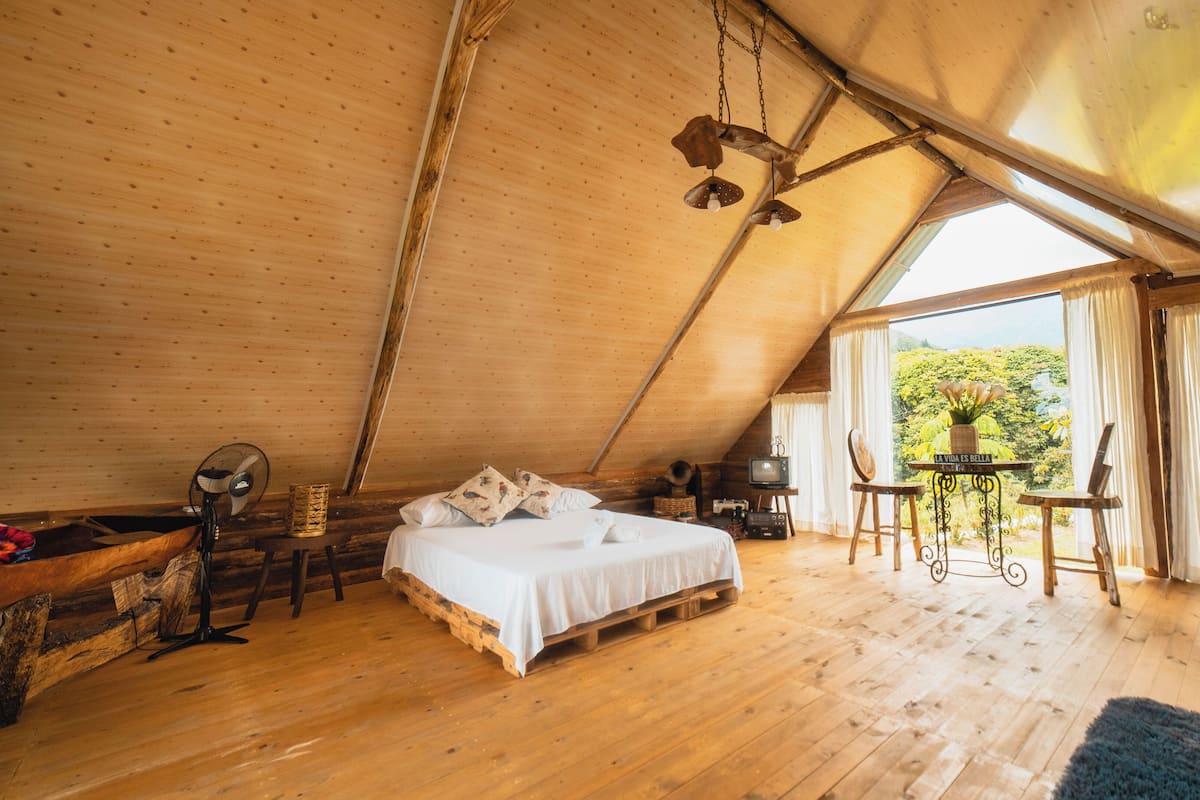 A cozy wooden room with a bed, a small table, and a television.