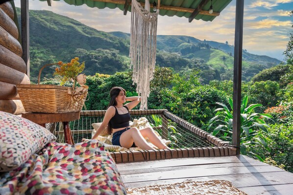 A hammock on a wooden deck with a view of lush green hills. - BOSQUE EL DESCANSO (Jamundi)