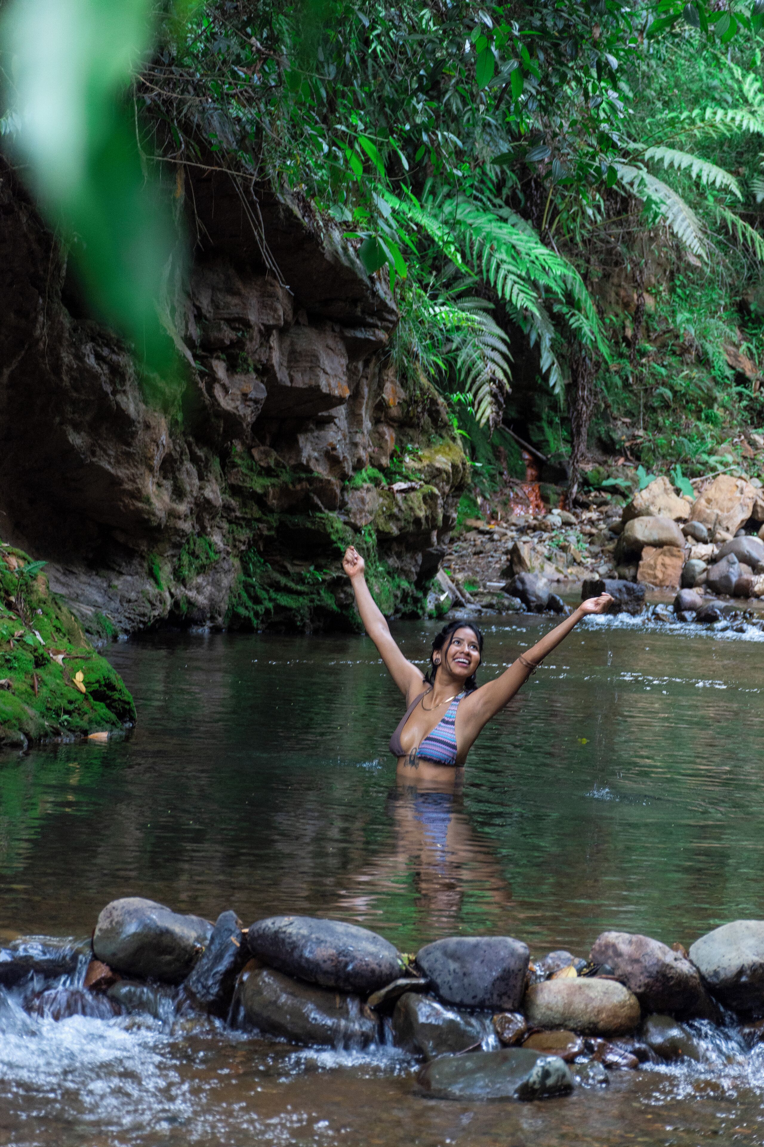 A woman in a natural setting with a stream and rocks.