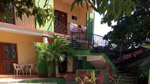 A courtyard with a paved area, potted plants, and a staircase leading to a balcony. - Casa Mamá Maya   (Puerto Escondido)