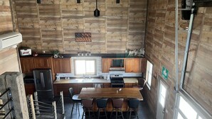 Eine moderne Küche mit Holzwänden, einer zentralen Kochinsel und einem Essbereich mit Stühlen.