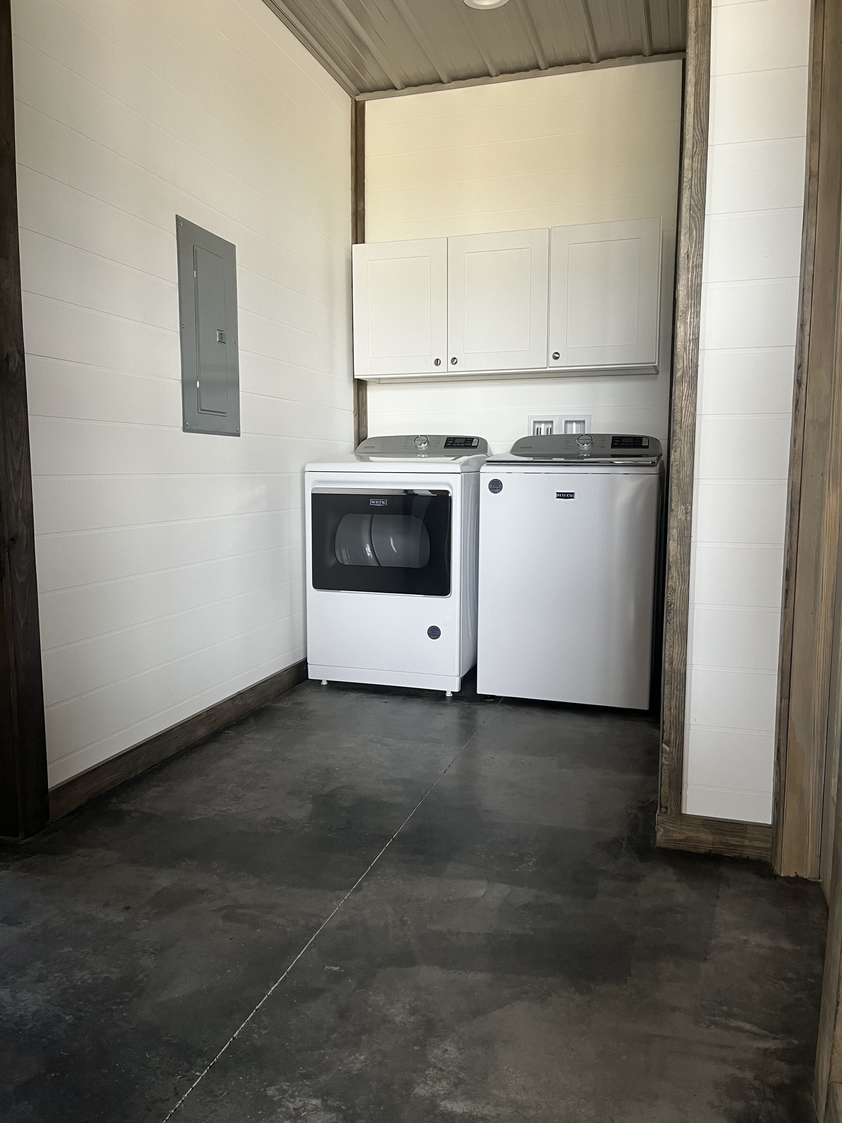 A laundry room with two white washing machines, a wooden door frame, and a white ceiling.