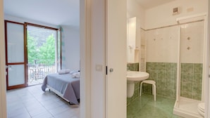 A bedroom with a bed, a balcony, and a bathroom with a sink and shower. - Porto Letizia Napoli 4, Porlezza, Italy (Porlezza)