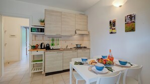 A modern kitchen with white cabinets, a microwave, and a dining area with a table set for two. - Porto Letizia Napoli 4, Porlezza, Italy (Porlezza)
