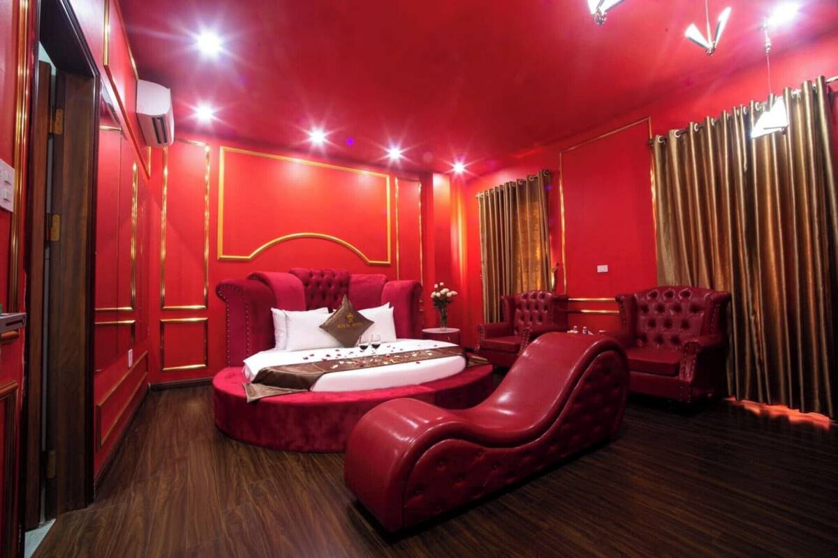 Ein luxuriöses Zimmer mit roter Farbgestaltung, darunter ein großes Bett, eine rote Liege und passendes rotes Mobiliar.