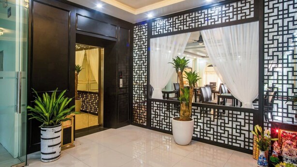 Eine Hotellobby im modernen Stil, mit einer Rezeption, Topfpflanzen und einem dekorativen Raumteiler.