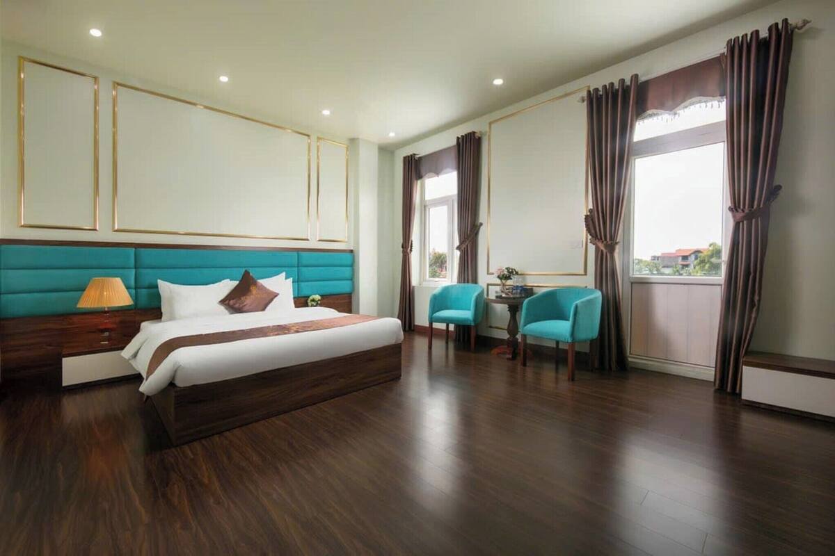 Ein Hotelzimmer mit einem großen Bett, einem Schreibtisch mit zwei Stühlen und Blick ins Freie.