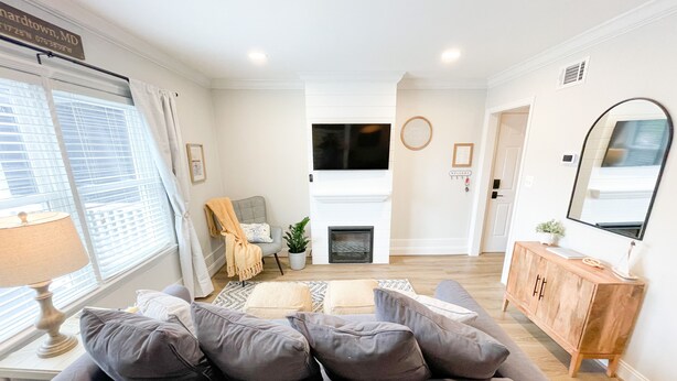 Una sala de estar moderna con un sofá gris, una chimenea, un televisor y un mueble de madera.