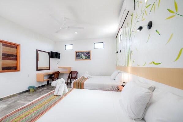 Habitación de hotel con dos camas, un escritorio, una silla, un televisor y una pared con diseño de hojas de bambú.
