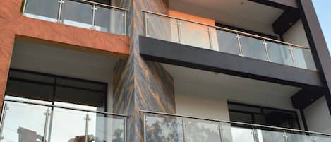 A modern hotel building with multiple balconies and large windows.