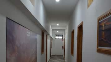 A hallway with patterned flooring, framed artwork on the walls, and doors leading to rooms.