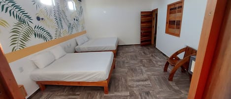 A room with two wooden beds, a wooden chair, a ceiling fan, and a wall with a leaf pattern.