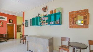 Un espace d’accueil comprenant un comptoir, des chaises et une bibliothèque contenant divers objets.