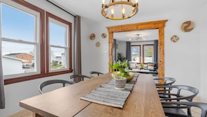 Ein Essbereich mit Holztisch, schwarzen Stühlen, einer gewebten Tischmatte und einem Blumentopf.