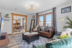 Ein modernes Wohnzimmer mit einer Ledersofa, einem Holztisch und einem großen Fenster mit Vorhängen.