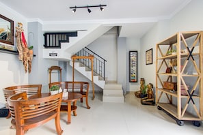 Un espacio habitable amplio con un comedor, una escalera y una estantería de madera.