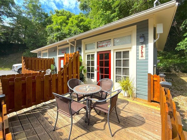 A small building with a red door, a sign reading 'Studio A,' and a patio with a table and chairs. - 66 Center - The Studio (Eureka Springs)