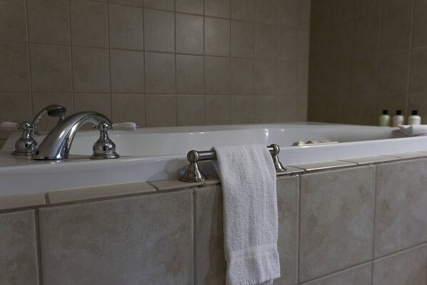 A bathroom with a white bathtub, a silver faucet, and a towel hanging on the side.