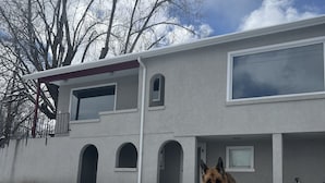 Uma casa com uma parede de pedra, uma janela grande e um cão na frente.