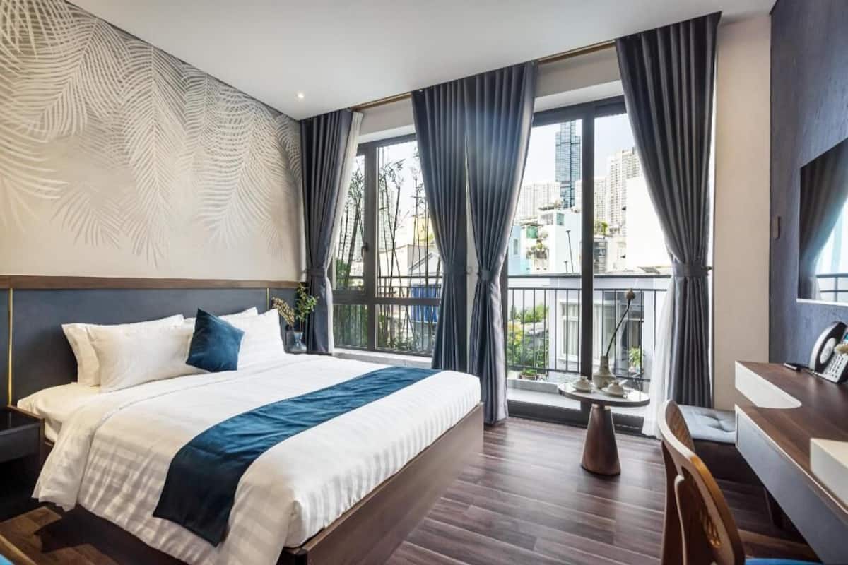 A modern hotel room with a large bed, a desk, and a view of the city.