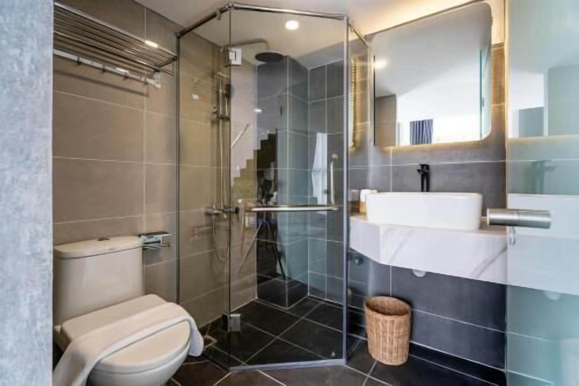 Un baño moderno con ducha de vidrio, lavamanos blanco y retrete.