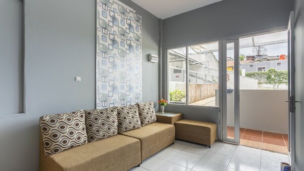 A modern living room with a sectional sofa, a patterned wall, and a sliding glass door leading to an outdoor area. - Collection O 3130 D'Valley View (Lembang)