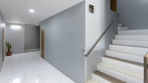 A modern interior with a staircase, white tiled flooring, and a potted plant. - Collection O 3130 D'Valley View (Lembang)