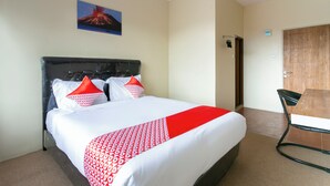 A hotel room with a bed, a wooden door, and a small table. - Collection O 3130 D'Valley View (Lembang)