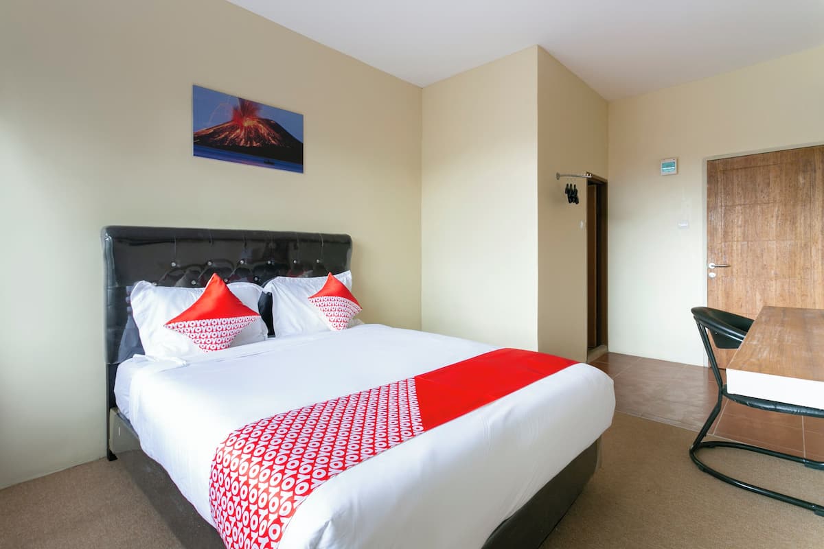 A hotel room with a bed, a wooden door, and a small table.