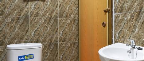Un baño con inodoro, lavabo y zona de ducha.
