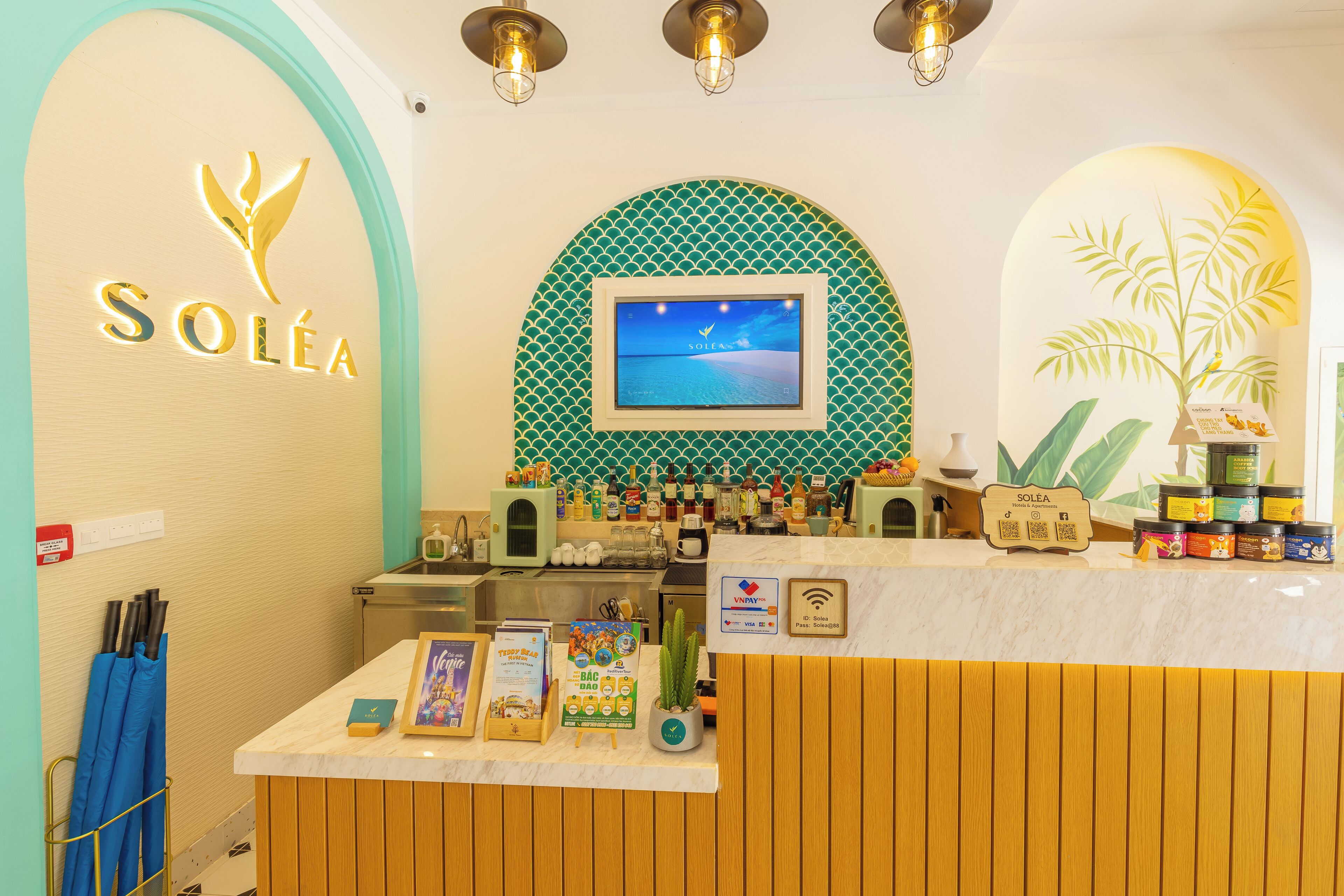 Un espace d’accueil avec une enseigne « SOLEA », un écran numérique affichant une scène de plage et une variété de produits exposés sur le comptoir.