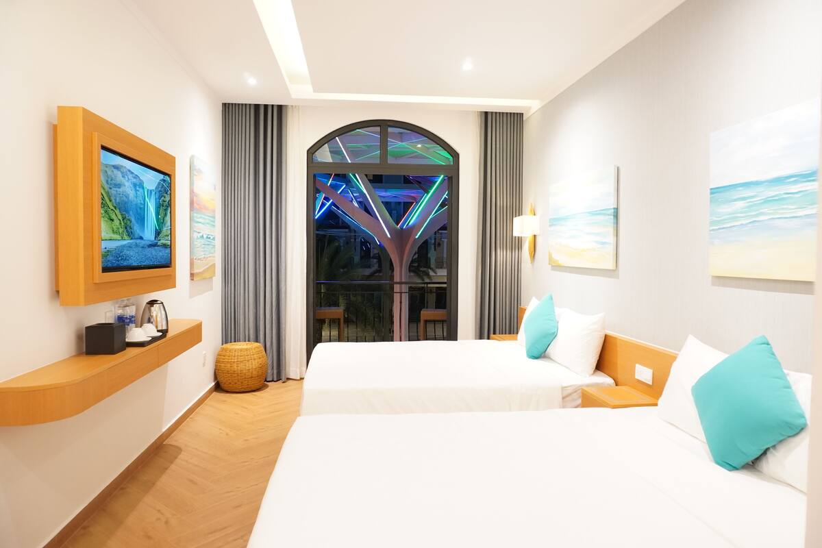 A hotel room with two beds, a TV, a balcony with a view, and a modern design.