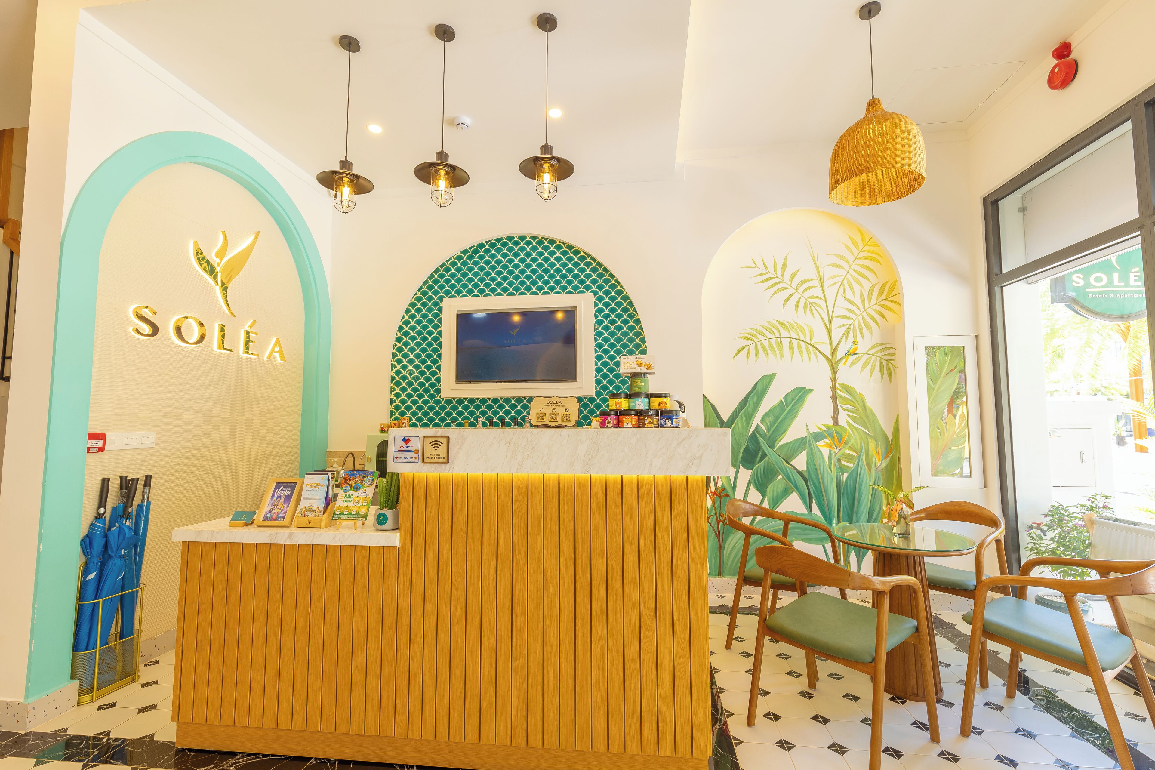 A reception area with a wooden counter, a TV screen, and a plant.